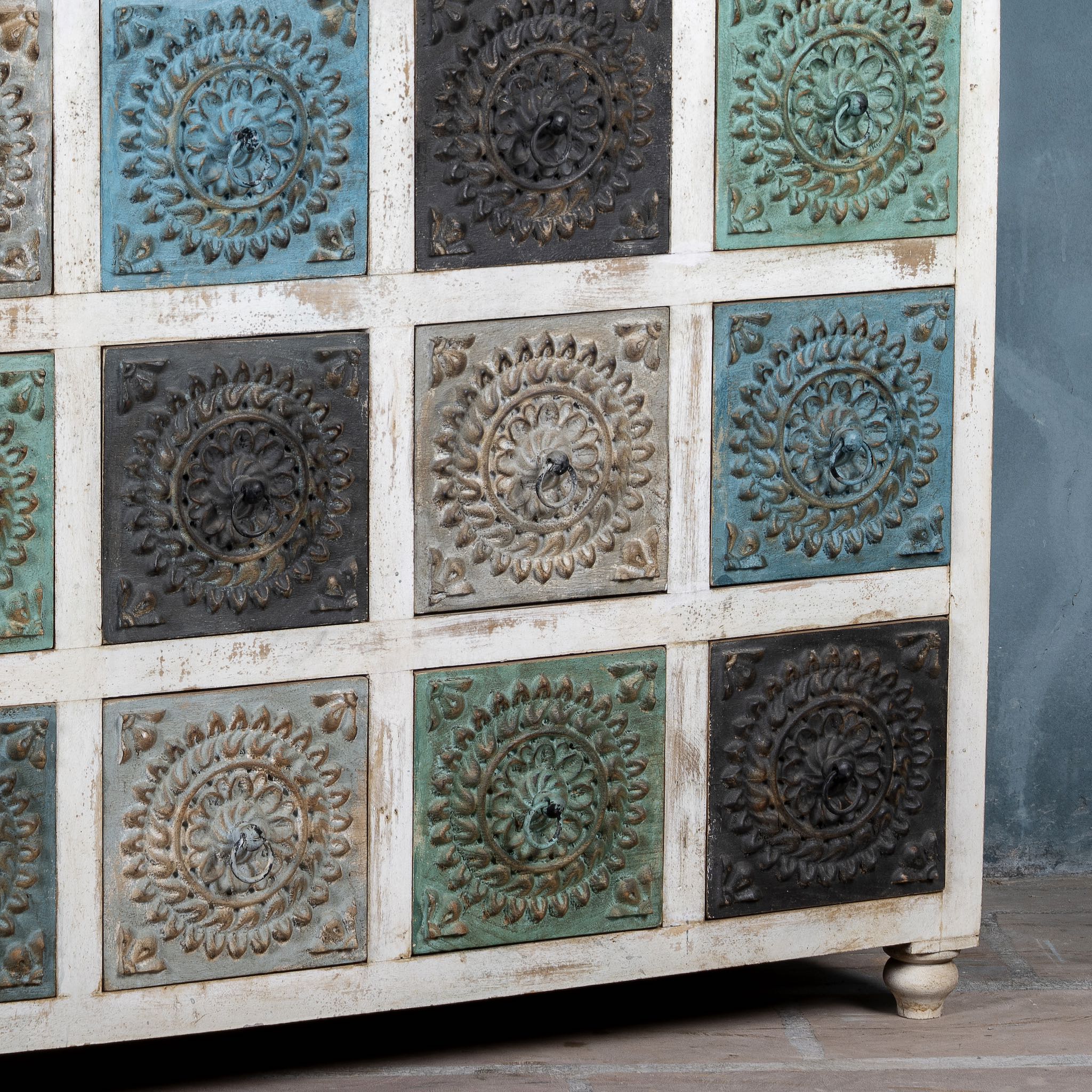 Close up image of a carved mango wood chest of drawers with twelve multicolour floral drawer fronts, 124 × 40 × 102 cm.