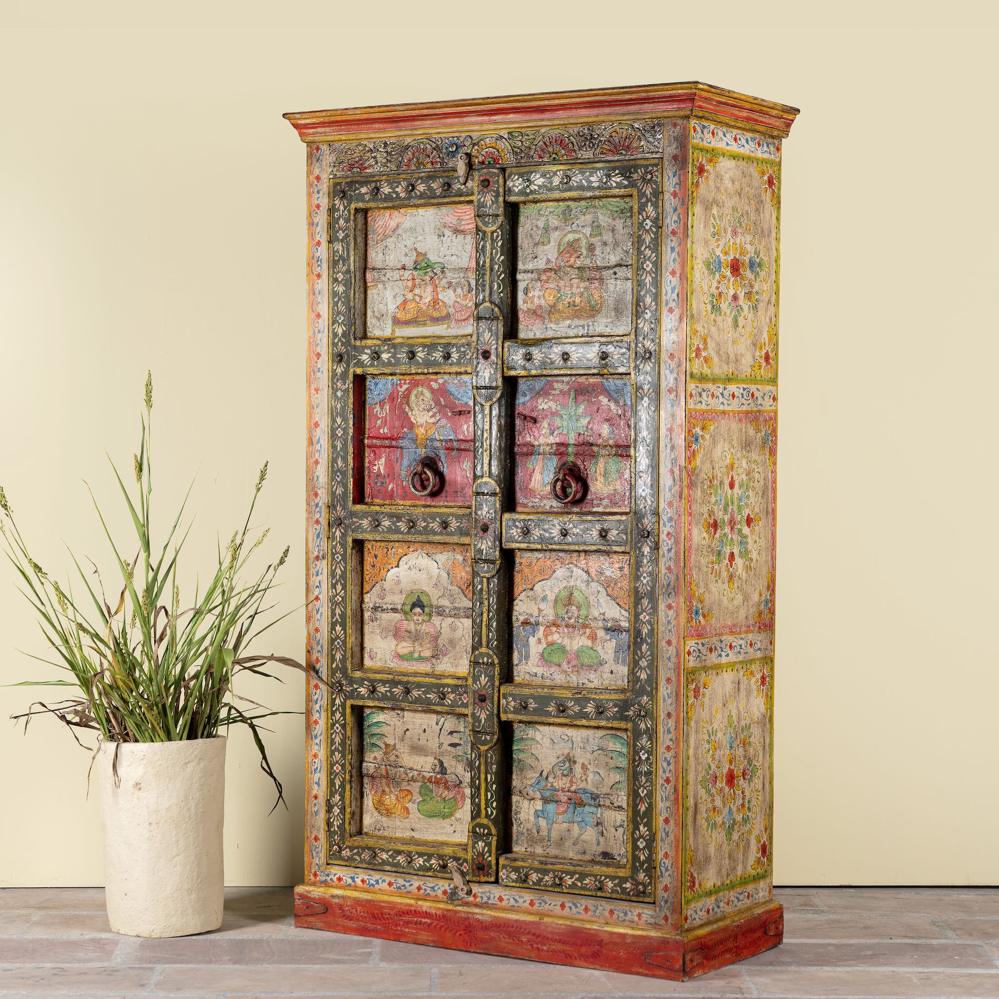 Side angle image of a hand painted teak wood cabinet with floral motifs, restored Indian furniture online; unique storage piece, 100 × 44 × 185 cm.