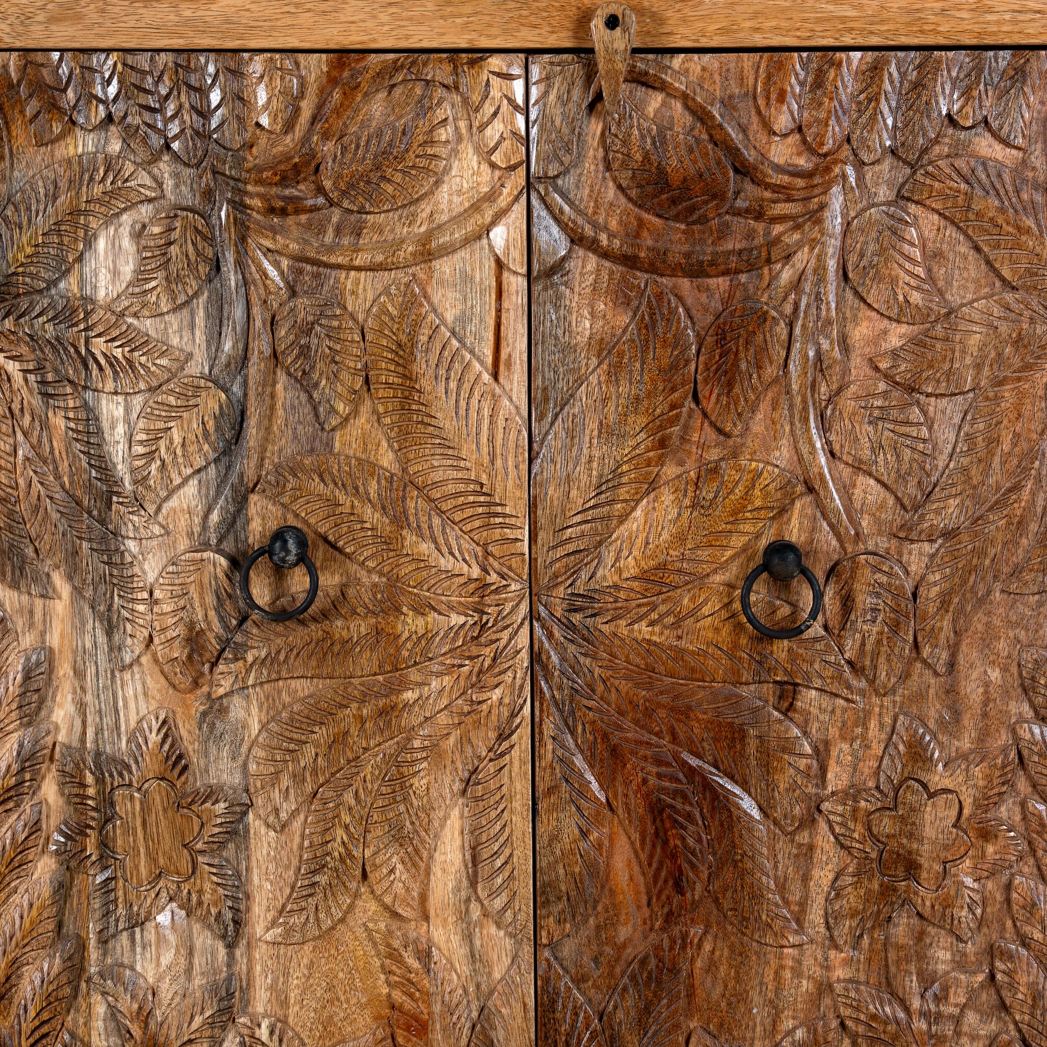 Close up image of a hand-carved mango wood cupboard Vansh with double doors featuring intricate floral and botanical motifs. A Mediterranean-inspired piece of Indian furniture offering functional storage and timeless artisan detail.