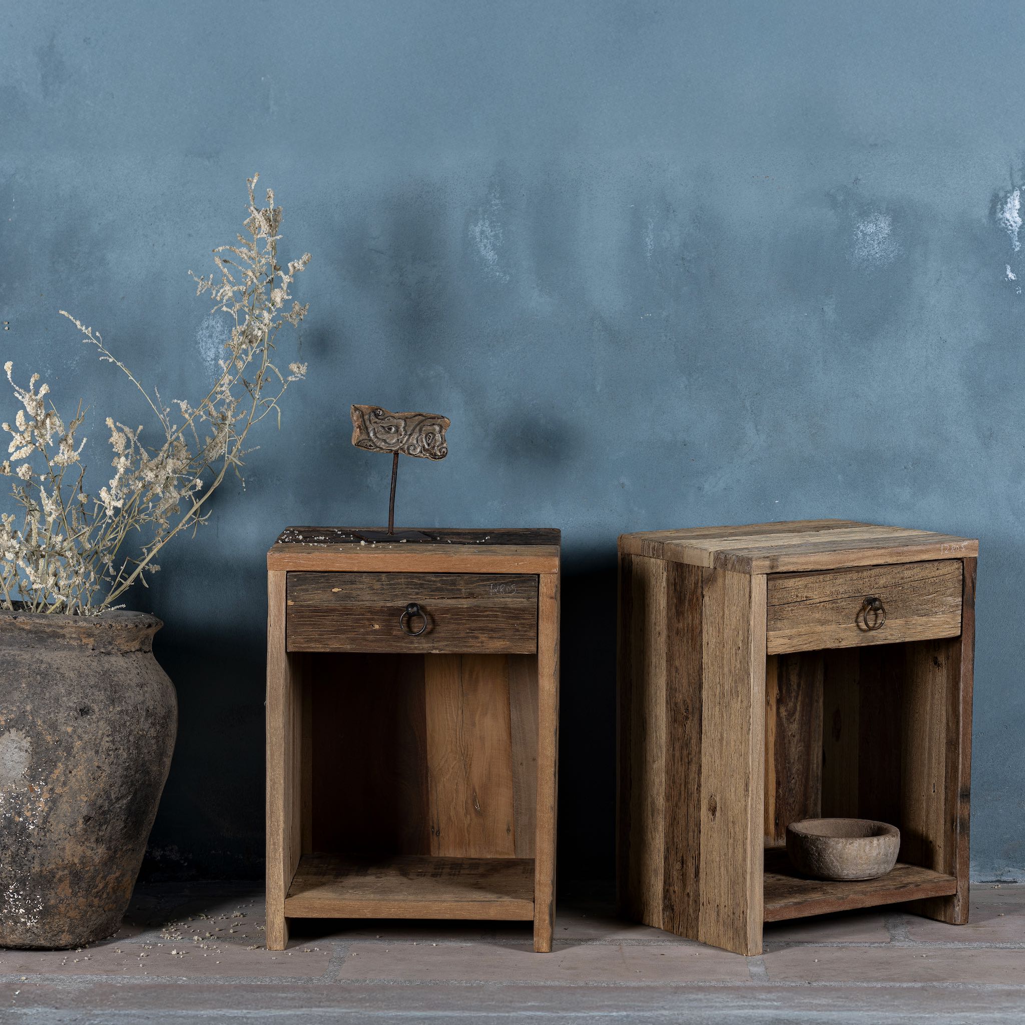 Side view image of a pair of bedside tables in Driftwood/ Wabi Sabi style crafted from recycled old wood, each featuring a single drawer with a metal ring pull and an open shelf below, showcasing natural wood grain and rustic textures.