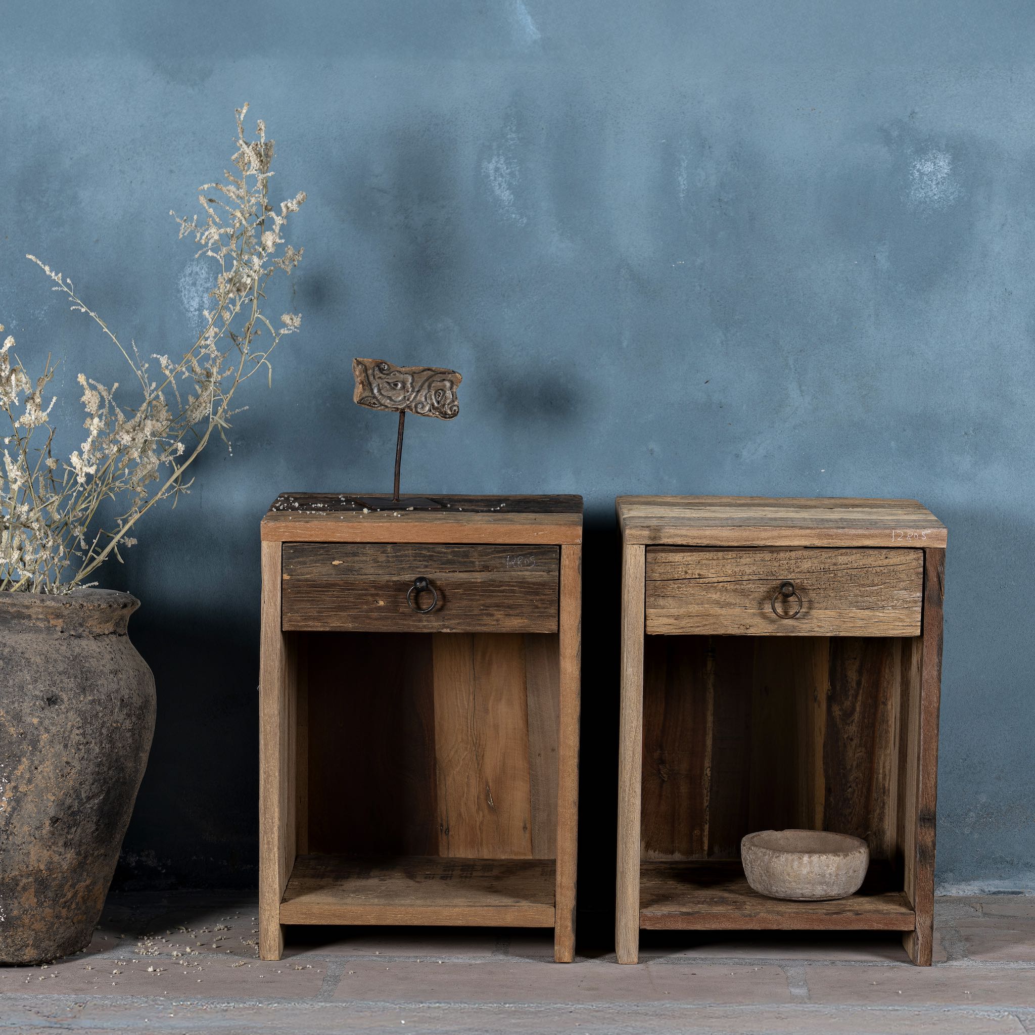 Front view image of a pair of bedside tables in Driftwood/ Wabi Sabi style crafted from recycled old wood, each featuring a single drawer with a metal ring pull and an open shelf below, showcasing natural wood grain and rustic textures.