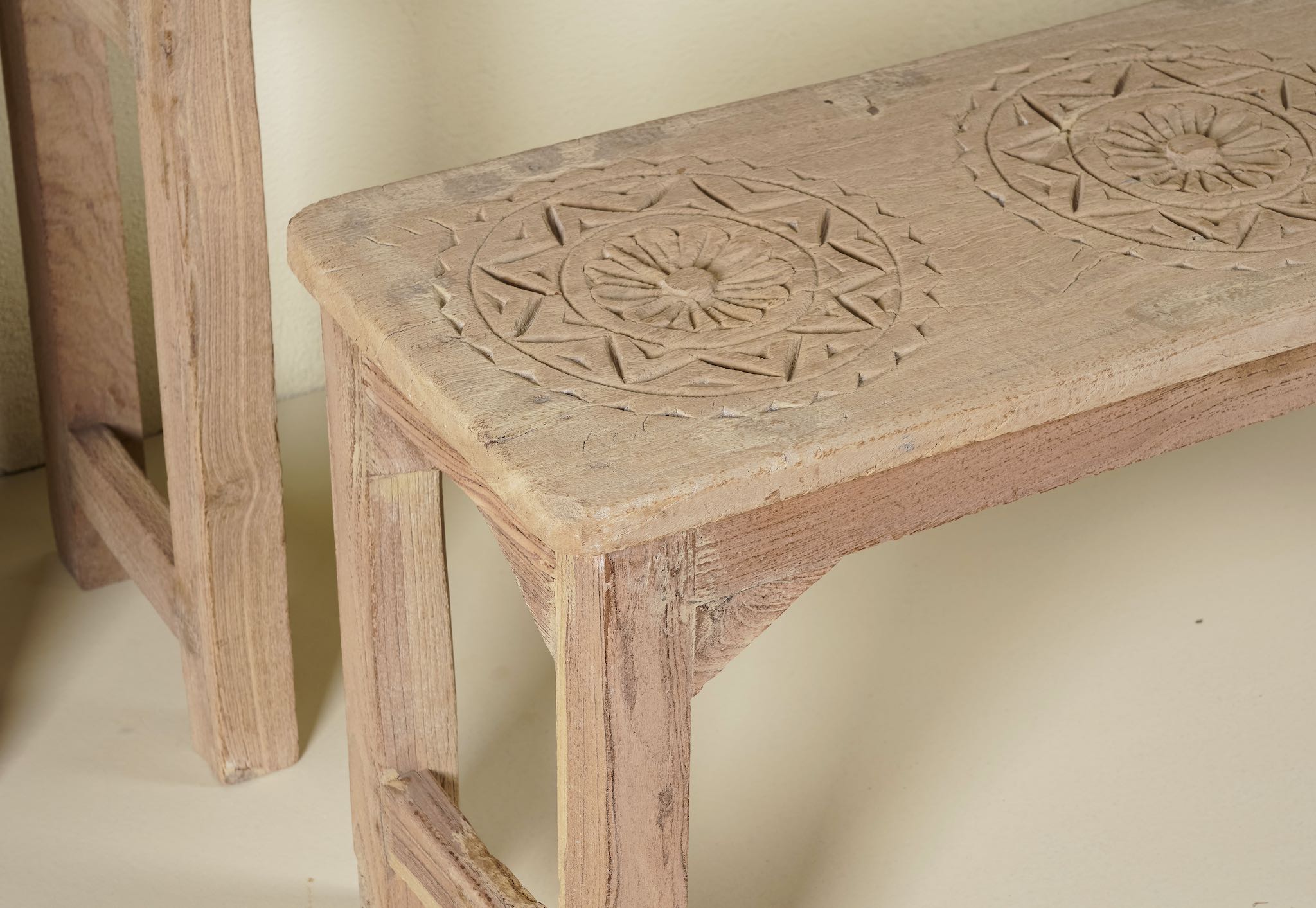 Close up image of a teak wood bench set made from refurbished wood with hand-carved detailing and rustic finish, 120 × 30 × 65 cm.