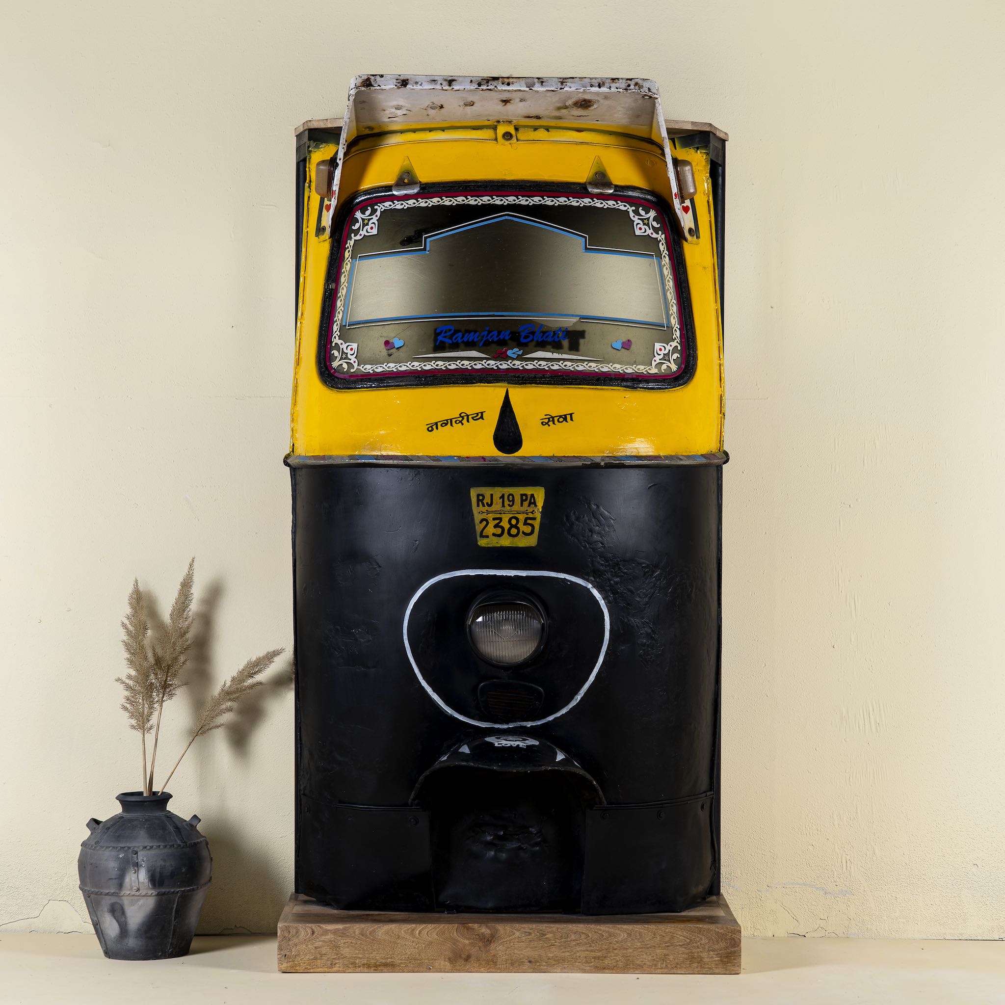 Unique bar table crafted from the front part of an old Indian rickshaw, featuring vibrant yellow and black paint with original details and functioning light.