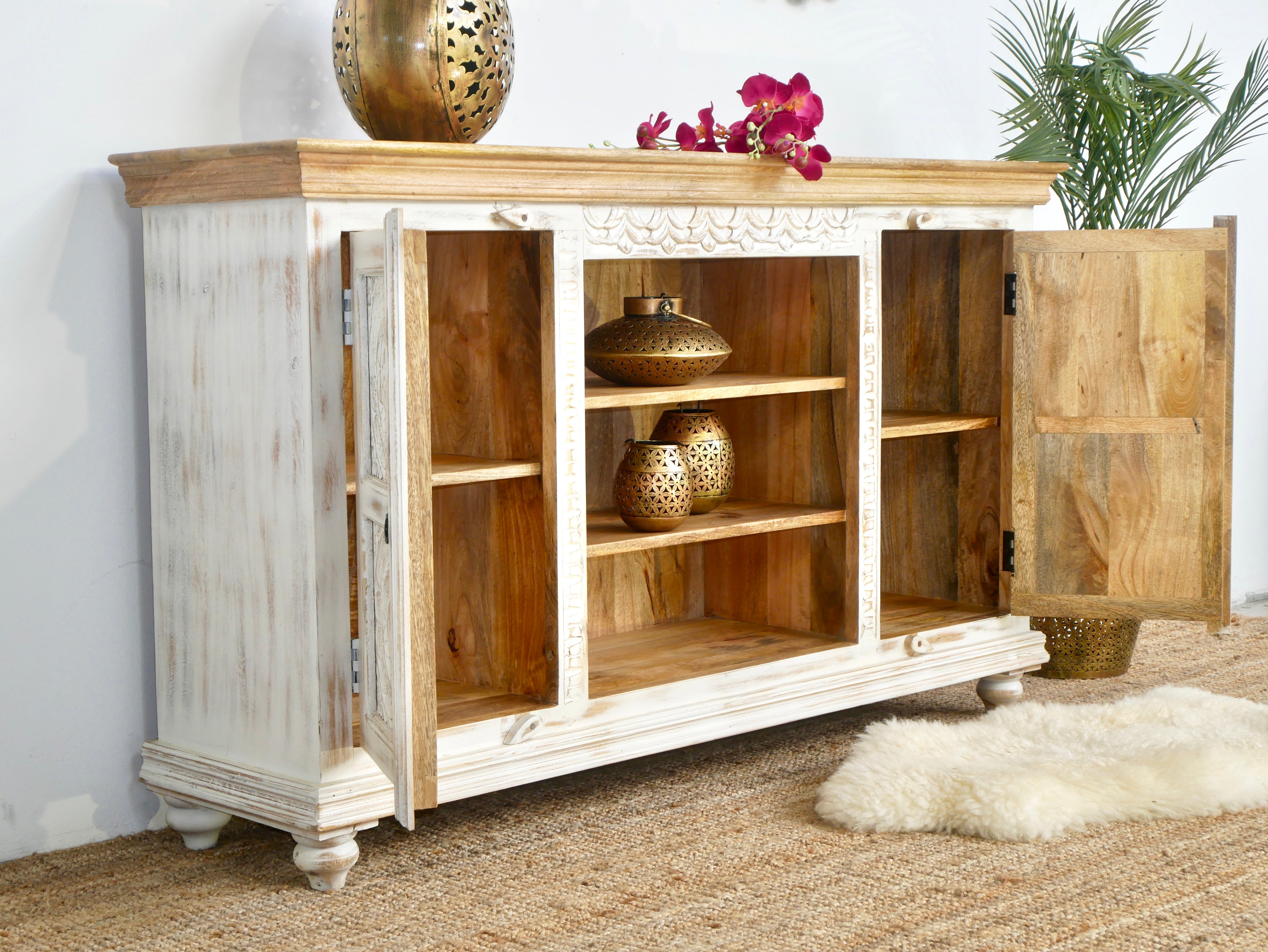 Side angle image of a carved mango wood console table with Indian motifs and natural finish; vintage furniture with 3 compartments and 2 drawers, 150 × 75 × 40 cm.
