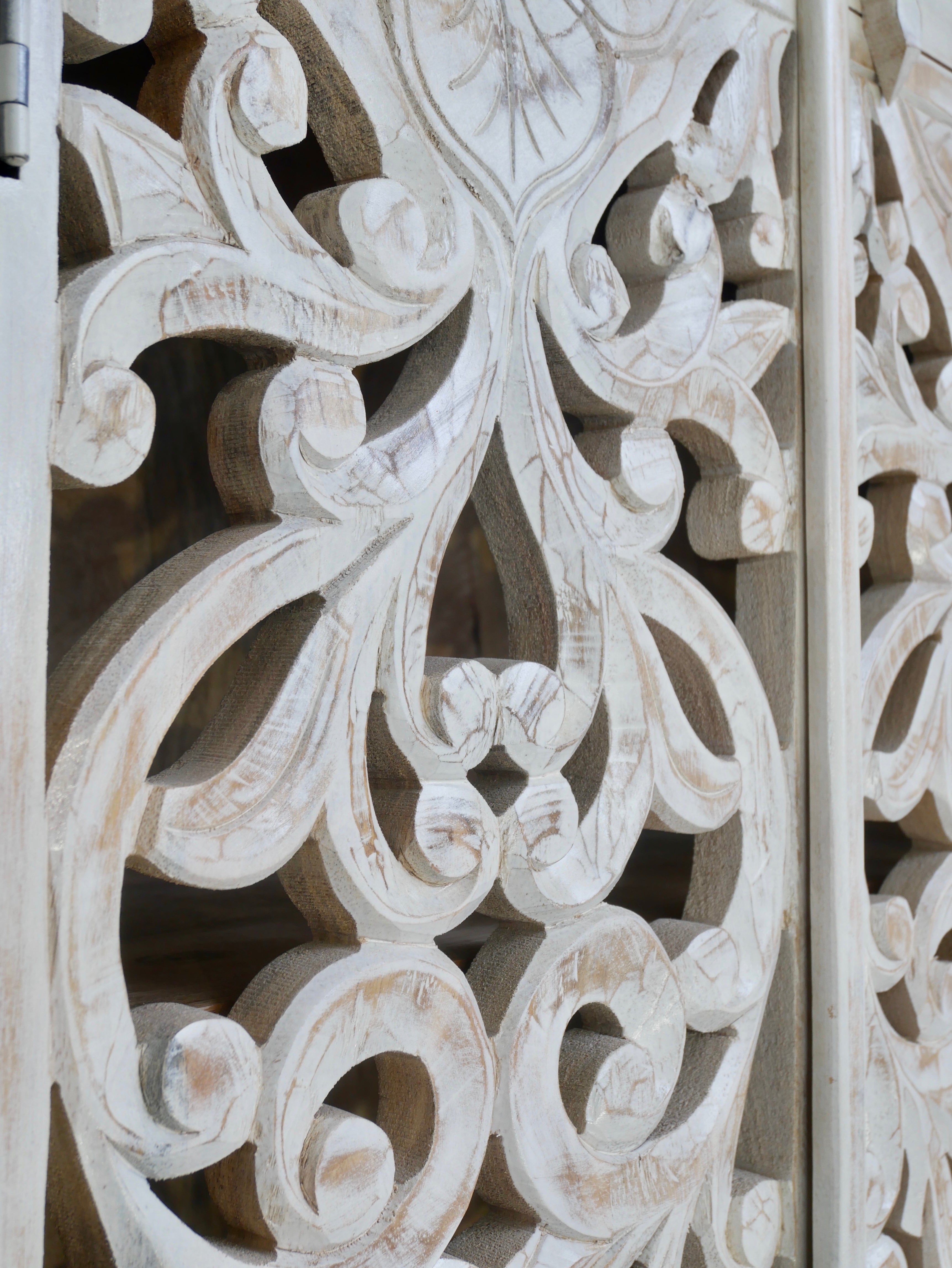 Close up image of a hand-carved mango wood cabinet with floral and geometric motifs in white-washed finish – carved wooden furniture with Mediterranean-inspired design.