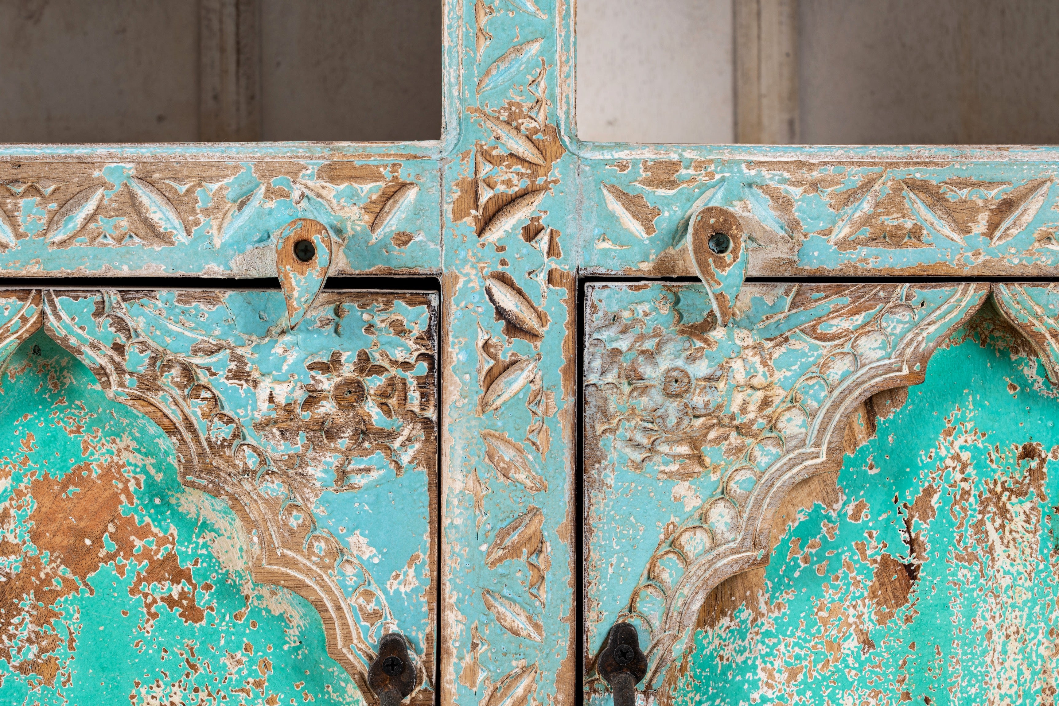 Close up image of a hand-carved mango wood shelf with arched open display and lower cabinets – vintage home decoration piece in distressed pastel blue finish with Indian architectural detailing.