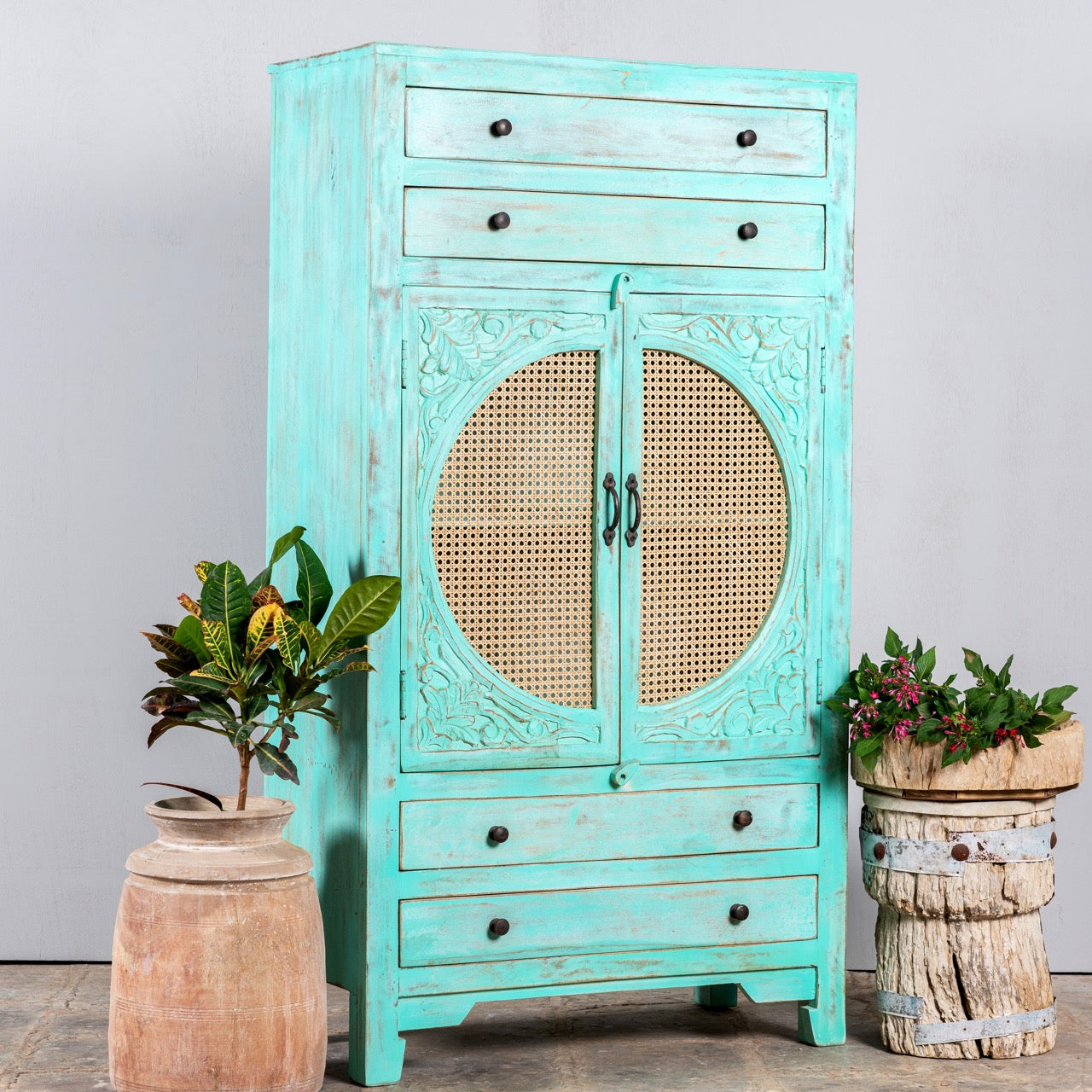 Side angle image of a Vintage furniture cabinet in turquoise-washed mango wood with rattan door panels and hand-carved engravings, 80 × 148 × 40 cm.