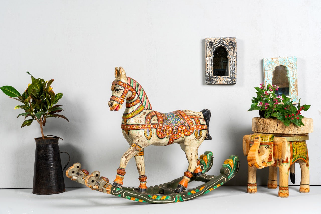 Side angle image of a hand-painted mango wood rocking horse “Gita” in Rajasthani style – colourful Indian home accessory and mango wood decor piece, 104x78x30cm.