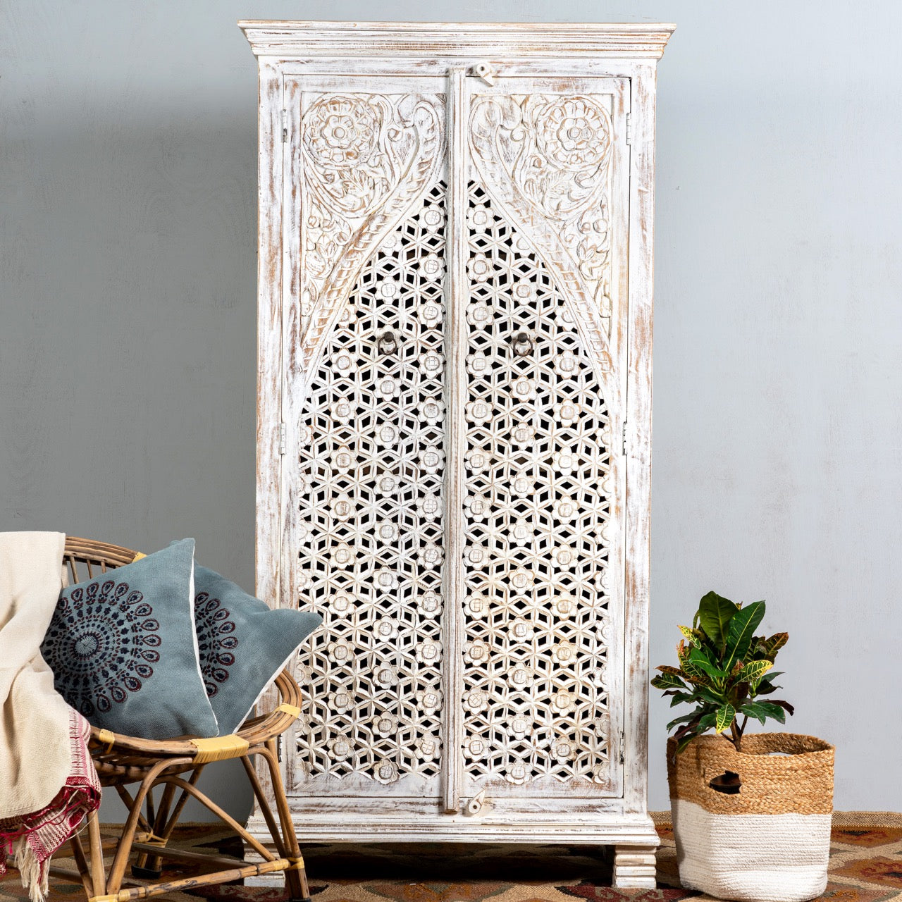 Lifestyle image of a white-washed hand-carved wooden wardrobe made of solid mango wood, vintage furniture with Mediterranean Ibiza style, 180 × 90 × 40 cm.