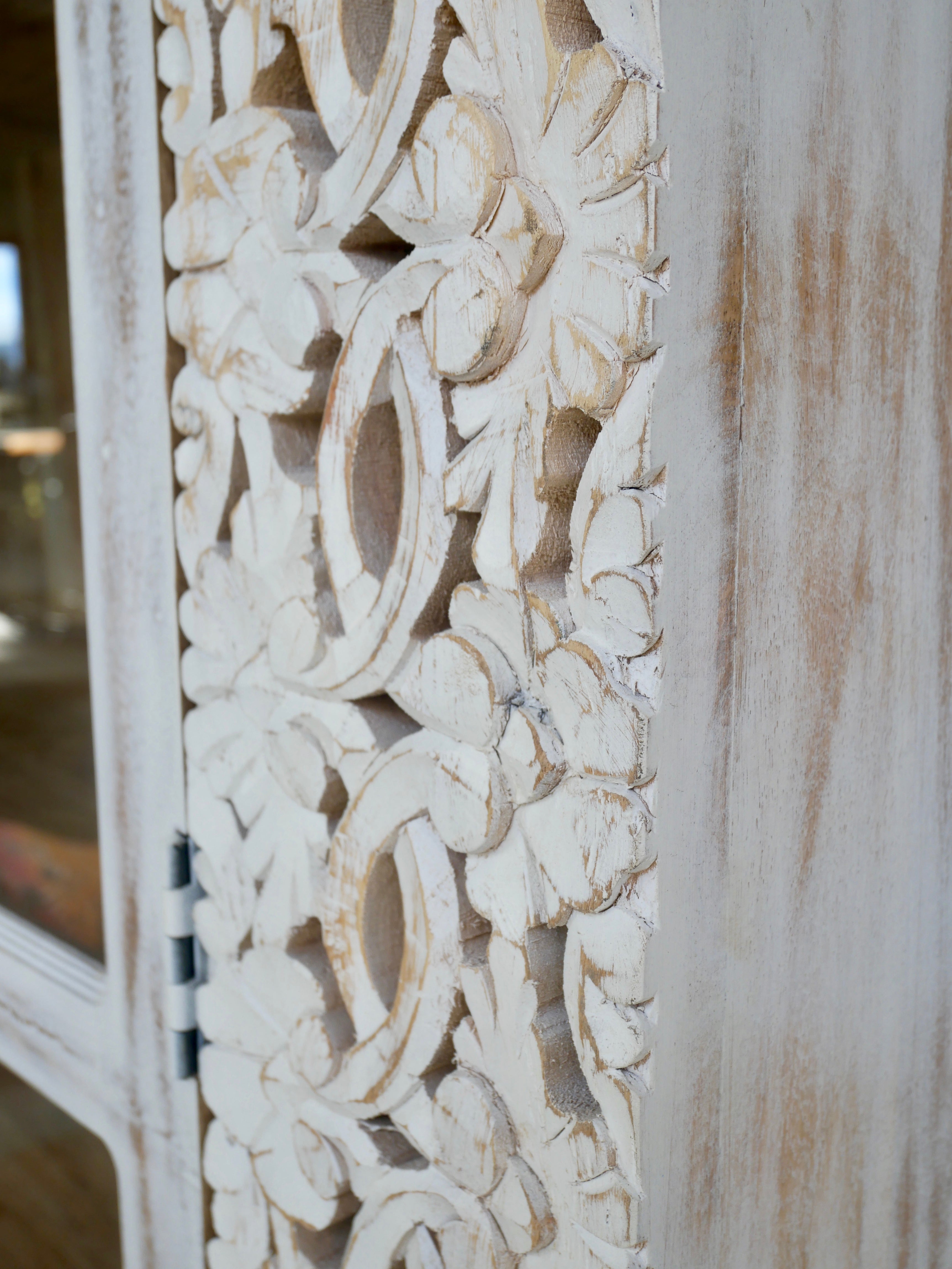 Close up image of a handcrafted mango wood cabinet with glass-panelled doors and internal storage – carved wood furniture made from sustainable mango wood with unique natural grain.