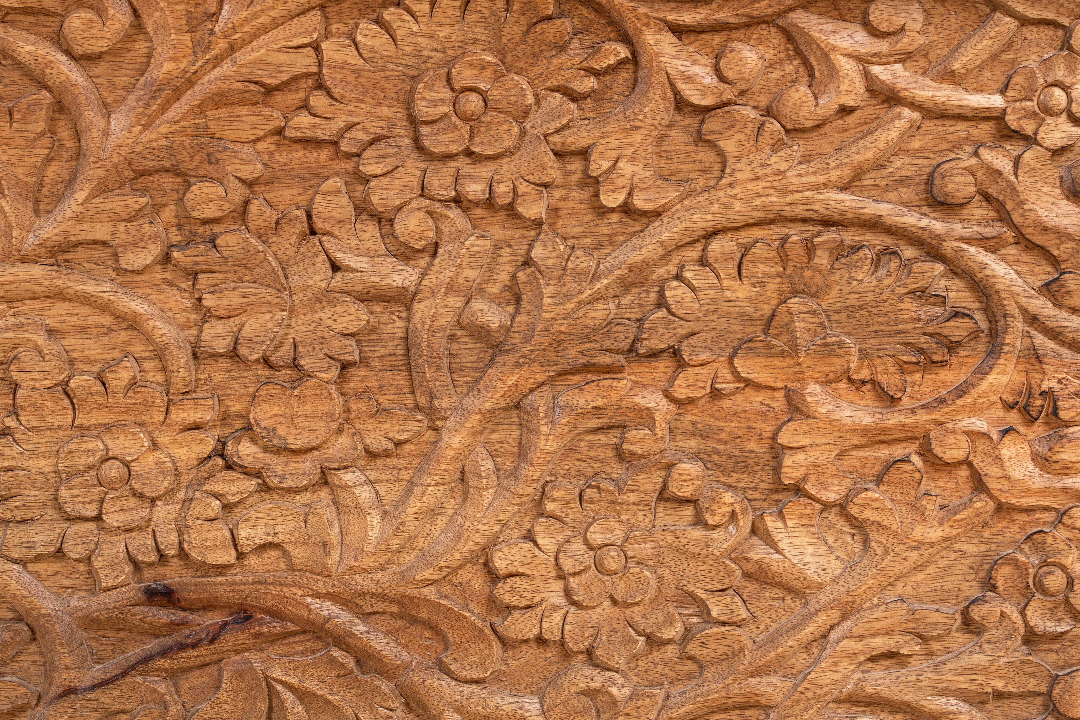 Close up image of a hand-carved mango wood storage chest with floral detailing and iron fittings – wooden carved chest ideal for use as elegant bedroom furniture or storage.