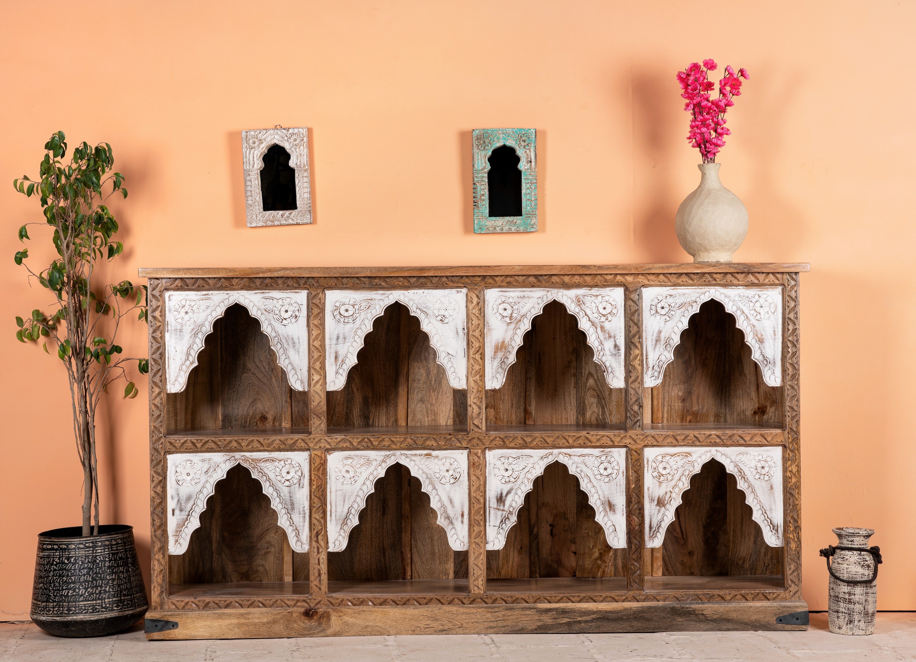 Handcrafted mango wood shelf with eight compartments and ornate carvings, featuring whitewashed accents, displayed in a home setting with decorative items and artwork above it.