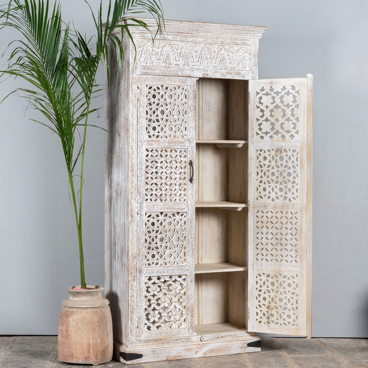 Side angle image with open door of hand-carved mango wood wardrobe with whitewashed finish, bedroom furniture wooden wardrobe with floral and geometric lattice doors, 90 × 190 × 40 cm.