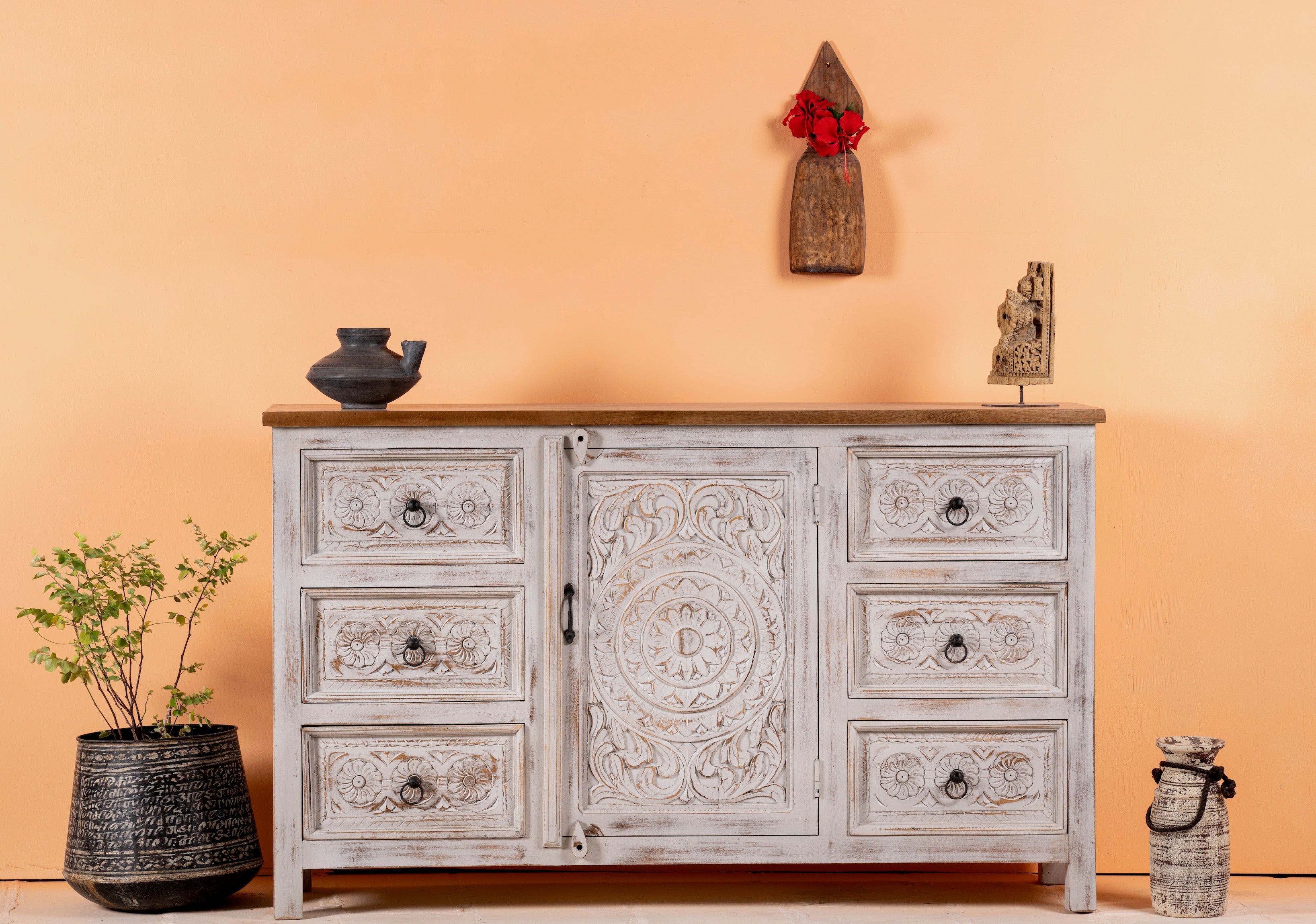 Life style image of a handcrafted mango wood sideboard with carved floral motifs, whitewashed base and natural top; perfect for vintage home decor and living room furniture, 150 × 40 × 90 cm.