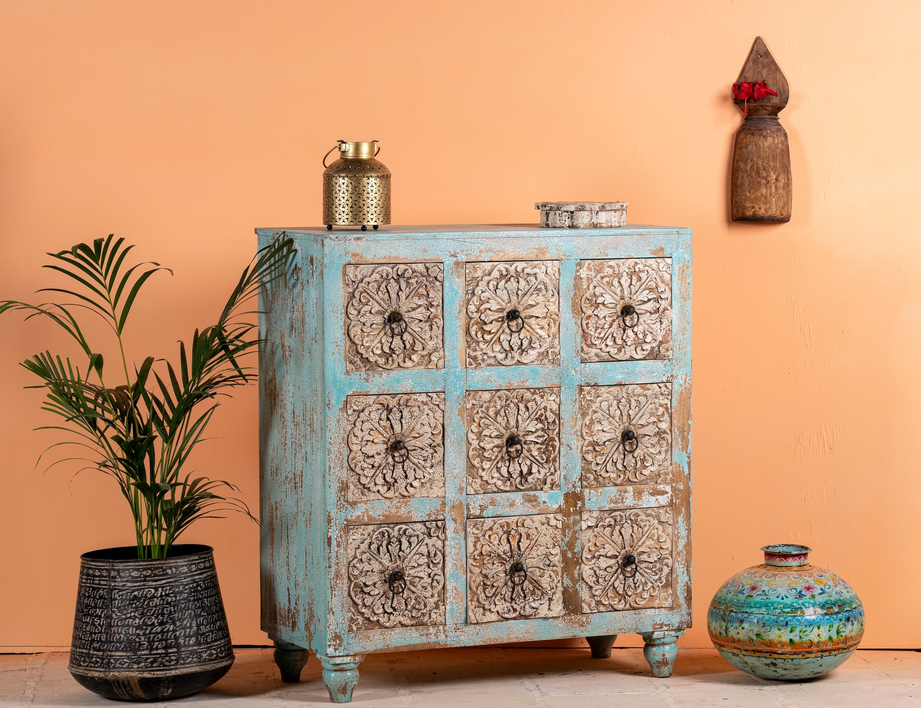 Side angle image of a hand-carved mango wood vintage chest of drawers with blue body and whitewashed floral fronts; perfect as an entryway table vintage accent, 90 × 100 × 40 cm.