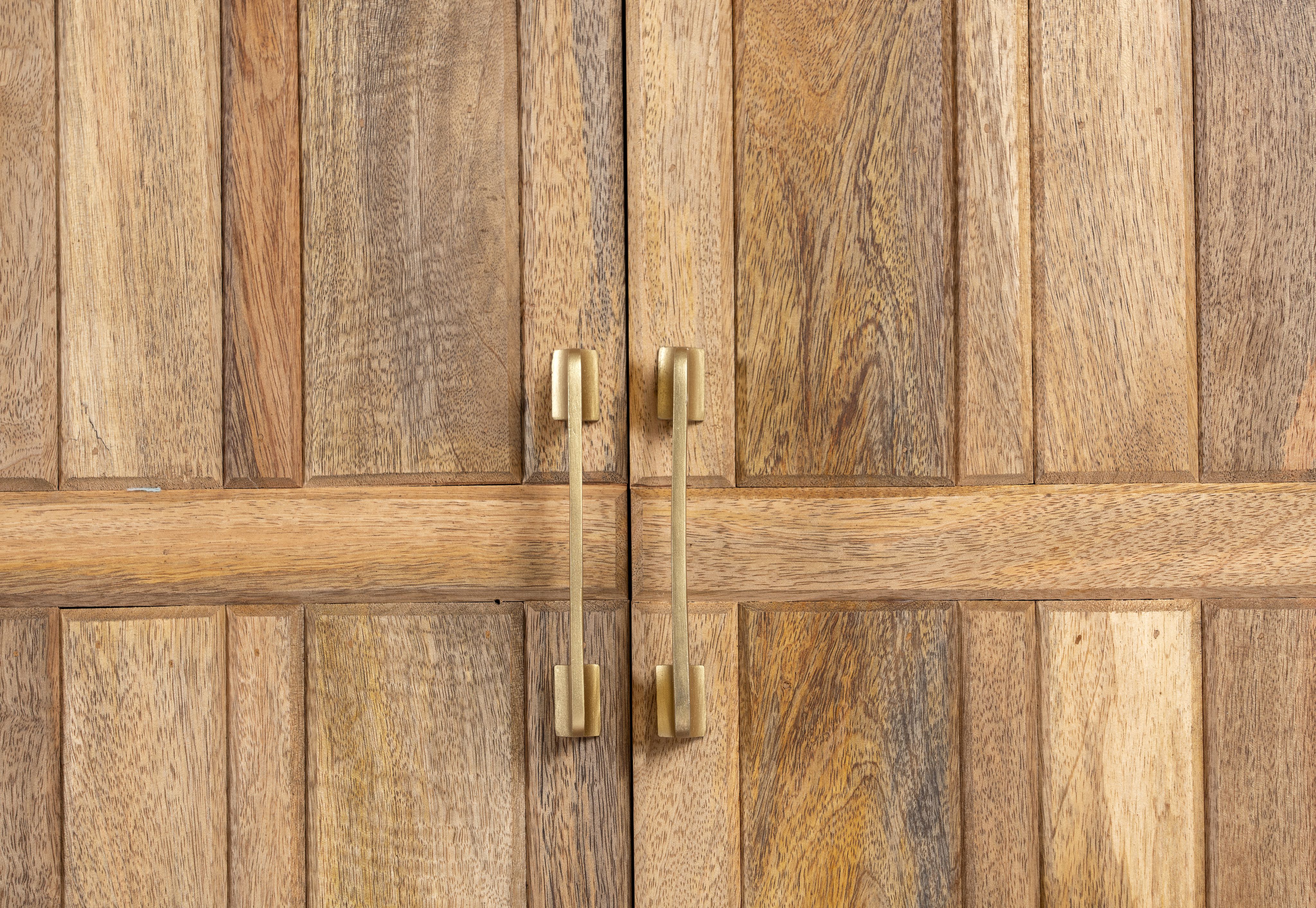 Close up image of a handcrafted mango wood sideboard with curved door panels and brass-plated legs—minimalistic style living room furniture with natural elegance.