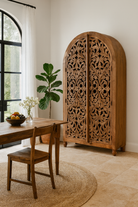 Lifestyle imagination of a of a hand carved wooden wardrobe with arc-shaped cabinet design in solid mango wood – Aranya model by Om Home & Garden