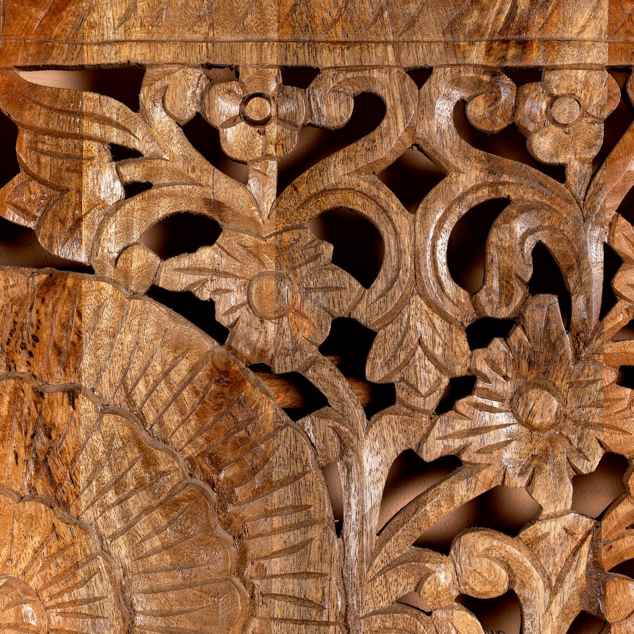 Close up image of a hand-carved mango wood wall panel with floral engravings in natural finish – Arusha model by Om Home & Garden