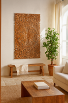Lifestyle scene with a hand-carved mango wood wall panel with floral motifs in natural finish – Arvavasu model by Om Home & Garden