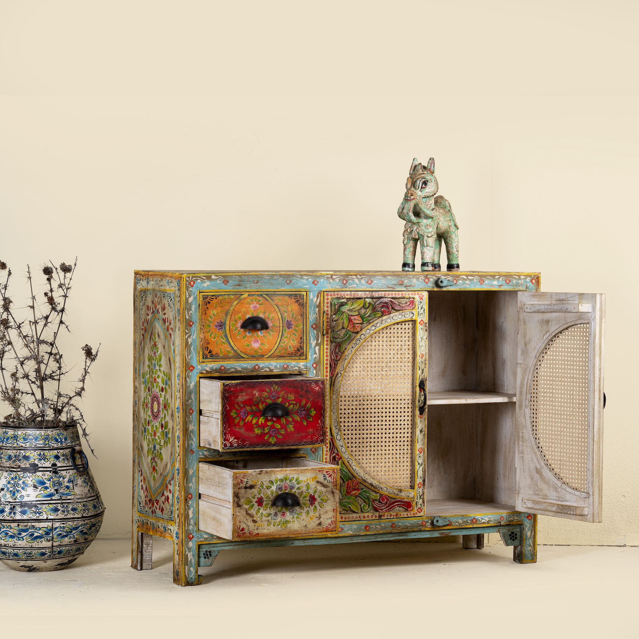 Side angle with open doors of a  hand painted sideboard Ashara made of mango wood with rattan inserts; Ibiza-inspired boho chic furniture, 120 × 40 × 92 cm.