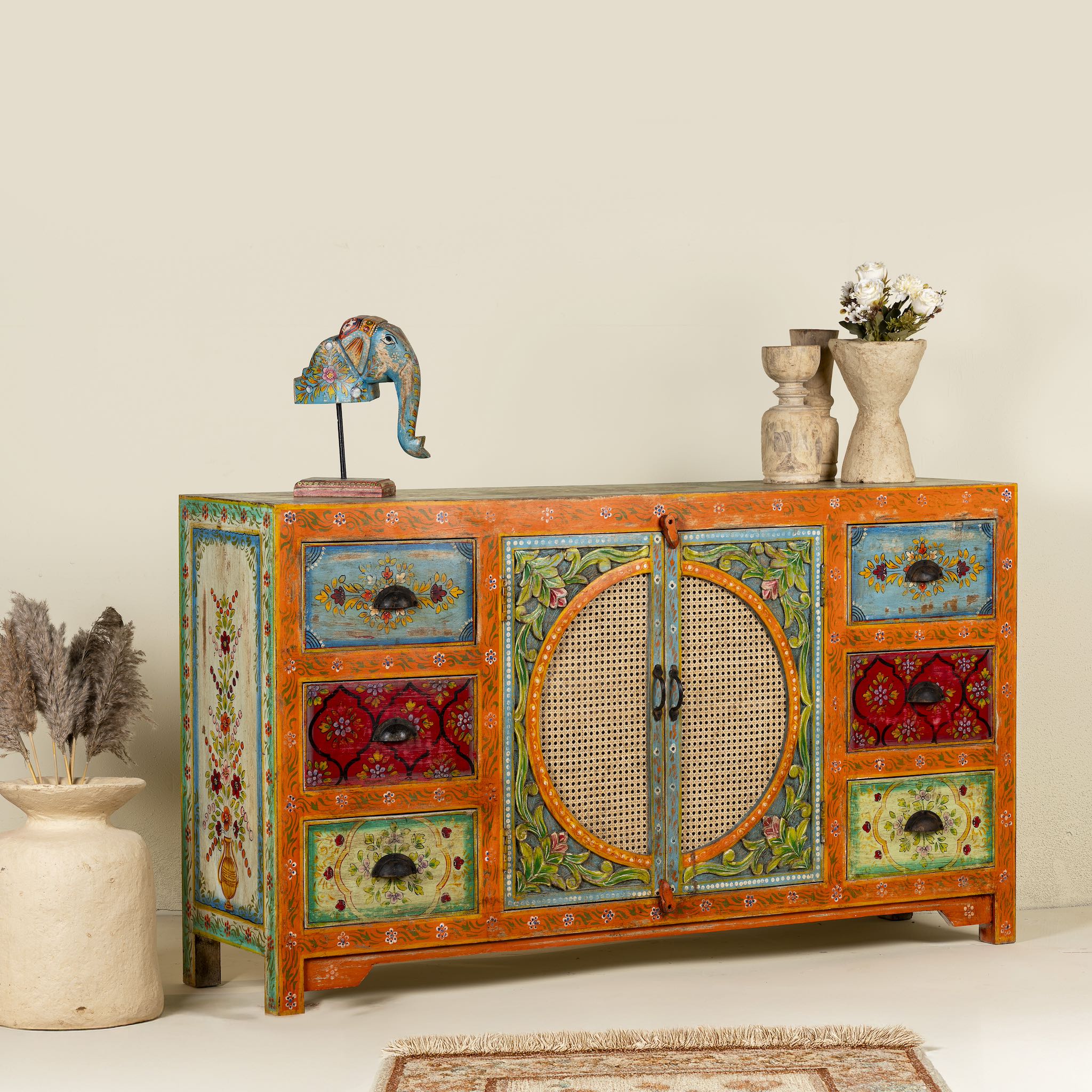 Side angle image of a vintage style furniture sideboard with hand-painted floral motifs and rattan door inserts, bohemian rattan door furniture, 160 × 40 × 90 cm.