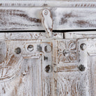 Close up image of a handcrafted cabinet with reclaimed Indian window frame doors, white-washed finish, and iron accents – vintage home decor with teak furniture appeal.