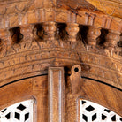 Close up image of a handcrafted carved wooden wardrobe in half-round design with whitewashed lattice panels – bedroom furniture with Mediterranean flair and artistic detail.