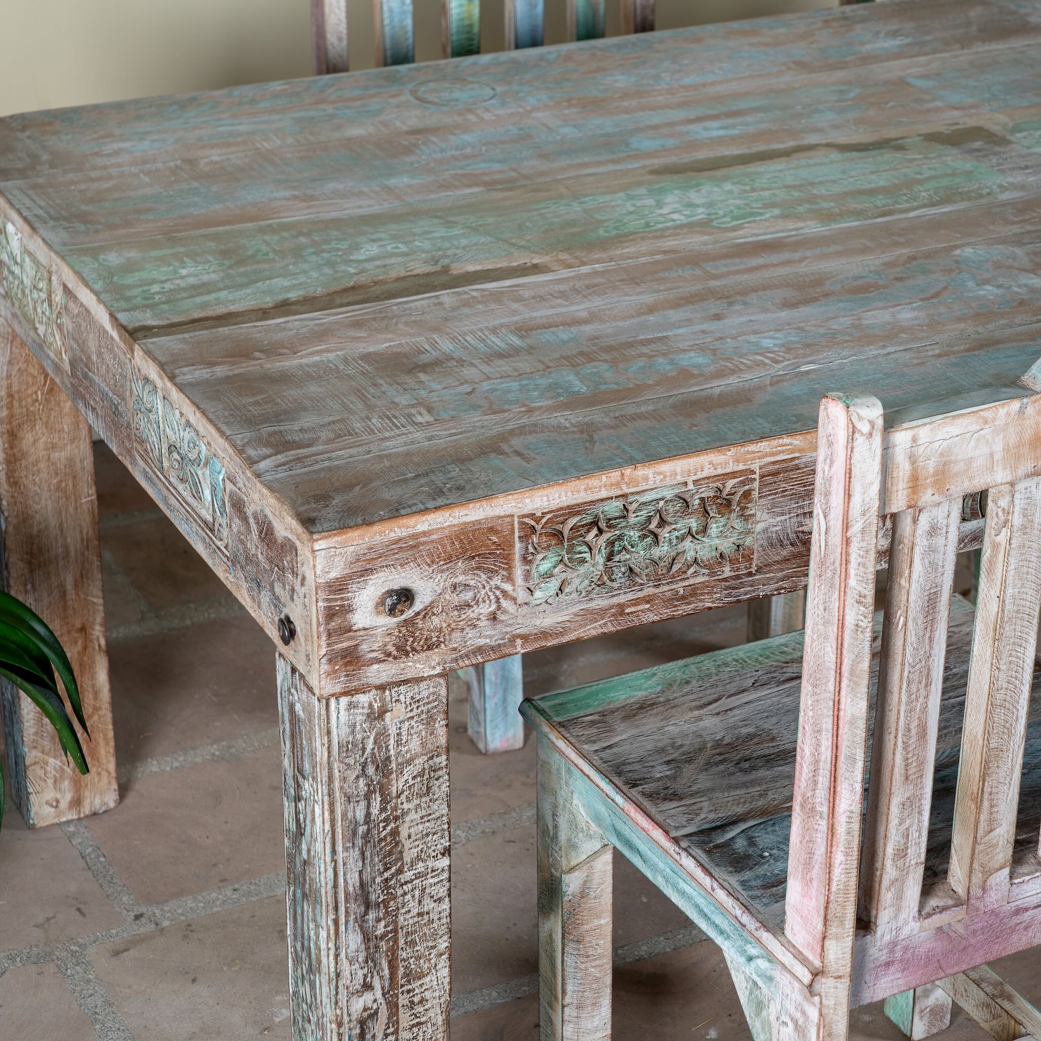 Close up image of a reclaimed wood dining set Ayla with one vintage table and six rustic chairs. A handcrafted bohemian interior piece combining sustainable materials with artistic, timeworn charm.