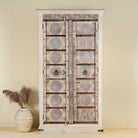 Front view of a old teak door wardrobe with floral carvings and original iron fittings.