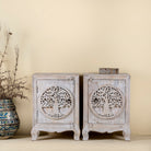 Pair of nightstands made from mango wood, featuring hand-carved tree of life designs on the doors and a whitewashed antique finish for a serene, artisanal look.