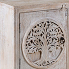 Close up picture of a pair of nightstands made from mango wood, featuring hand-carved tree of life designs on the doors and a whitewashed antique finish for a serene, artisanal look.