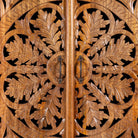 Close up image of a half-round mango wood wardrobe with floral carvings, a unique example of sustainable furniture and artisanal furniture.