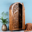 Open door image of a half-round mango wood wardrobe with floral carvings, a unique example of sustainable furniture and artisanal furniture.