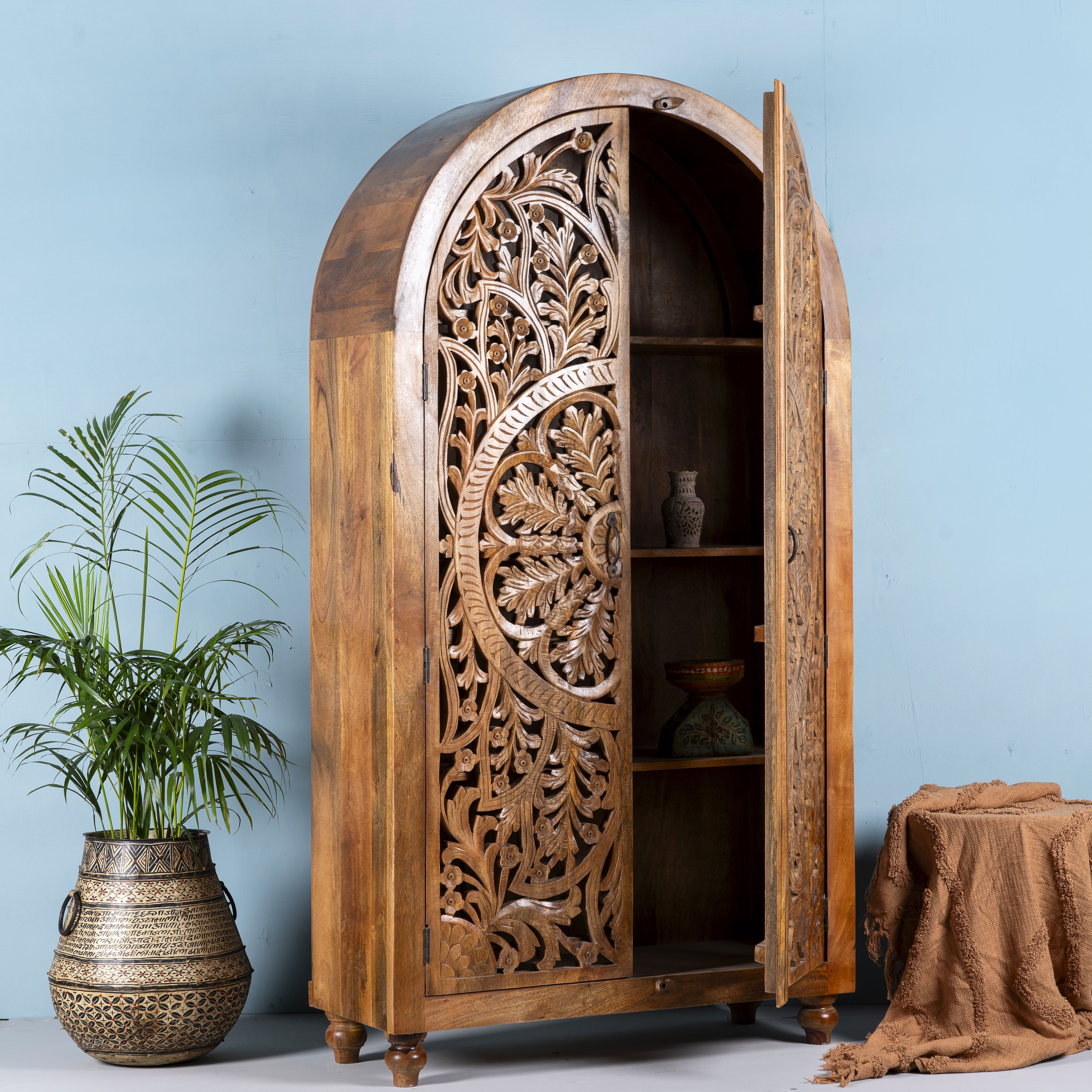 Open door image of a half-round mango wood wardrobe with floral carvings, a unique example of sustainable furniture and artisanal furniture.