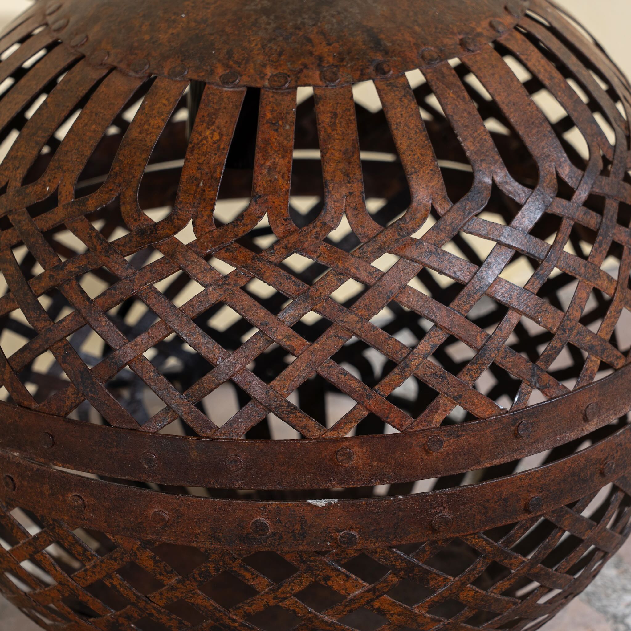 Close up image of a Champa hand crafted metal pendant light with spherical lattice design and iron chain—an artisan lighting piece from our collection of compact metal pendant lights and hand forged metal lamps.