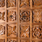 Close up image of a hand-carved mango wood wardrobe with floral motifs; wooden wardrobe in natural finish, 100 × 45 × 190 cm.