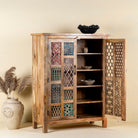 Side angle with open door image for a   artisan-made cabinet crafted from mango wood, featuring double doors adorned with a patchwork of colourful, intricately carved geometric panels, blending traditional craftsmanship with a vibrant, eclectic style.
