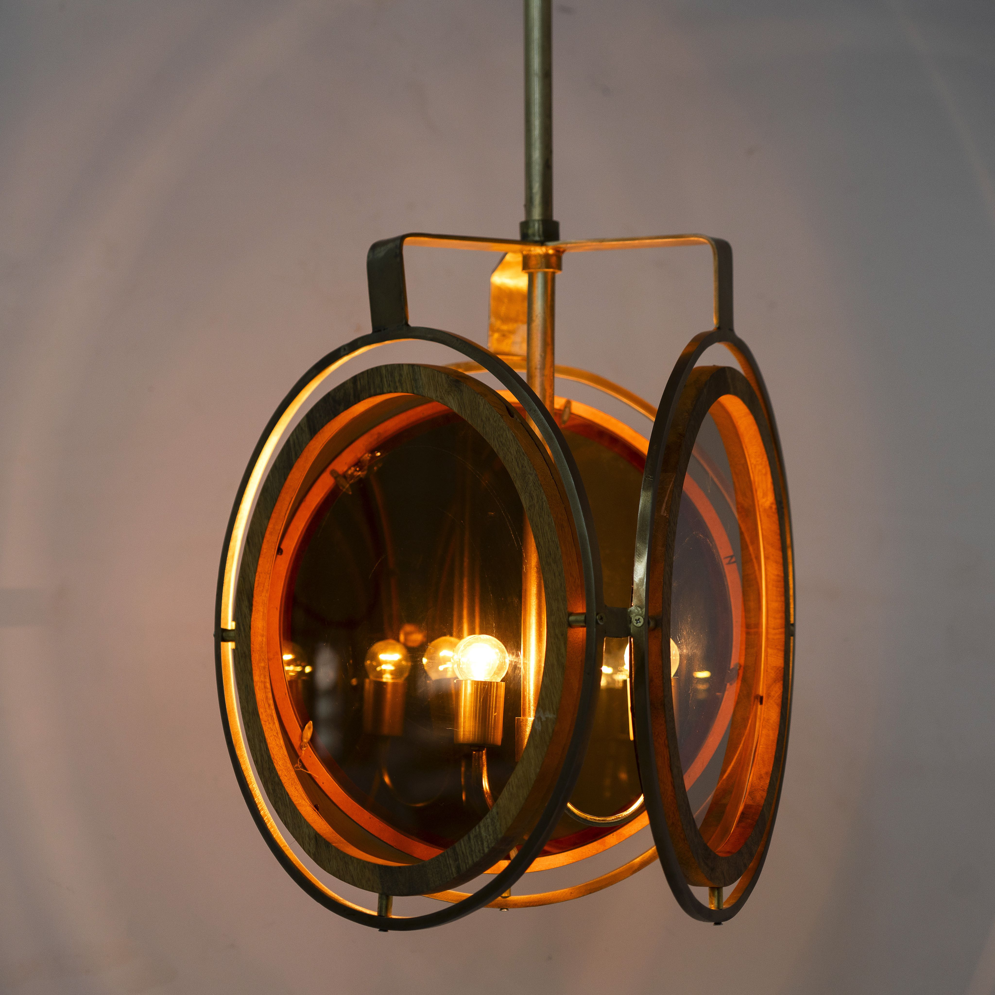 Image showing a lighted artsy pendant lamp with 3-circle mango wood and brass-plated design, tinted glass inserts – vintage lighting piece for dining rooms, kitchens, or stylish living areas.