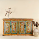 Front view image of a hand-painted sideboard made from reclaimed wood, featuring four intricately detailed doors with vibrant floral and geometric motifs in soft blues, yellows, and reds, finished with a distressed vintage patina for a charming, artisanal look.
