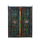 White background image of a hand-painted wall panel made from an old teak wood window frame, adorned with detailed floral motifs in shades of pink, red, green, and white against a deep blue background, framed by intricate carvings and colorful decorative accents.
