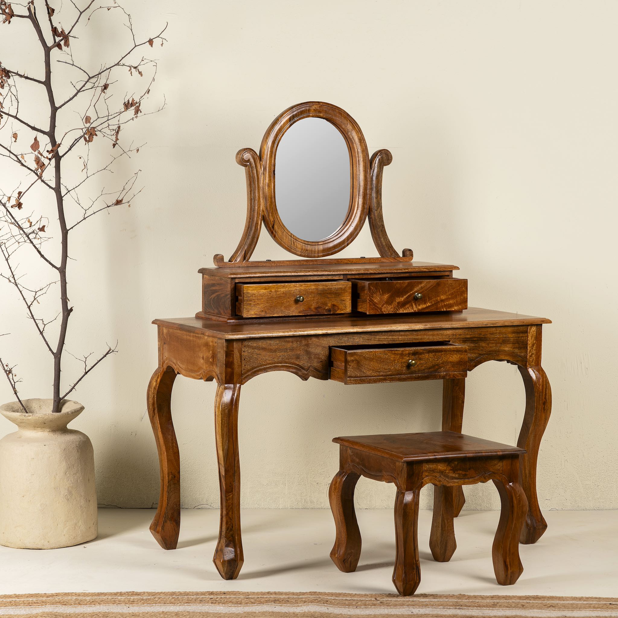 Side angle image of a handcrafted mango wood cosmetic table with a curved mirror and a matching chair.