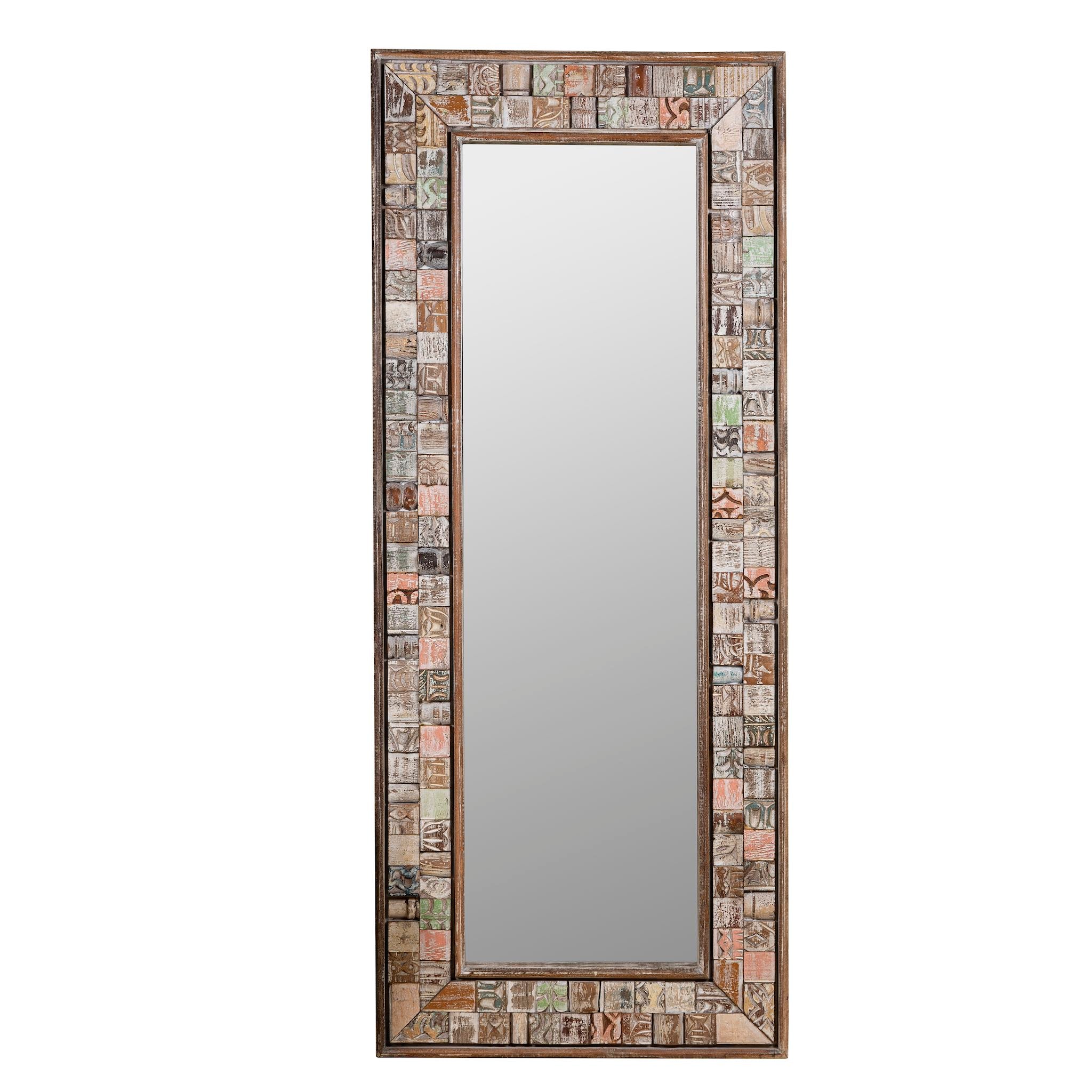 White background image of a rectangular mirror framed with reclaimed wood, featuring a mosaic-style border of intricately carved and coloured wooden tiles, each with unique textures and patterns, creating a rustic and artistic statement piece.
