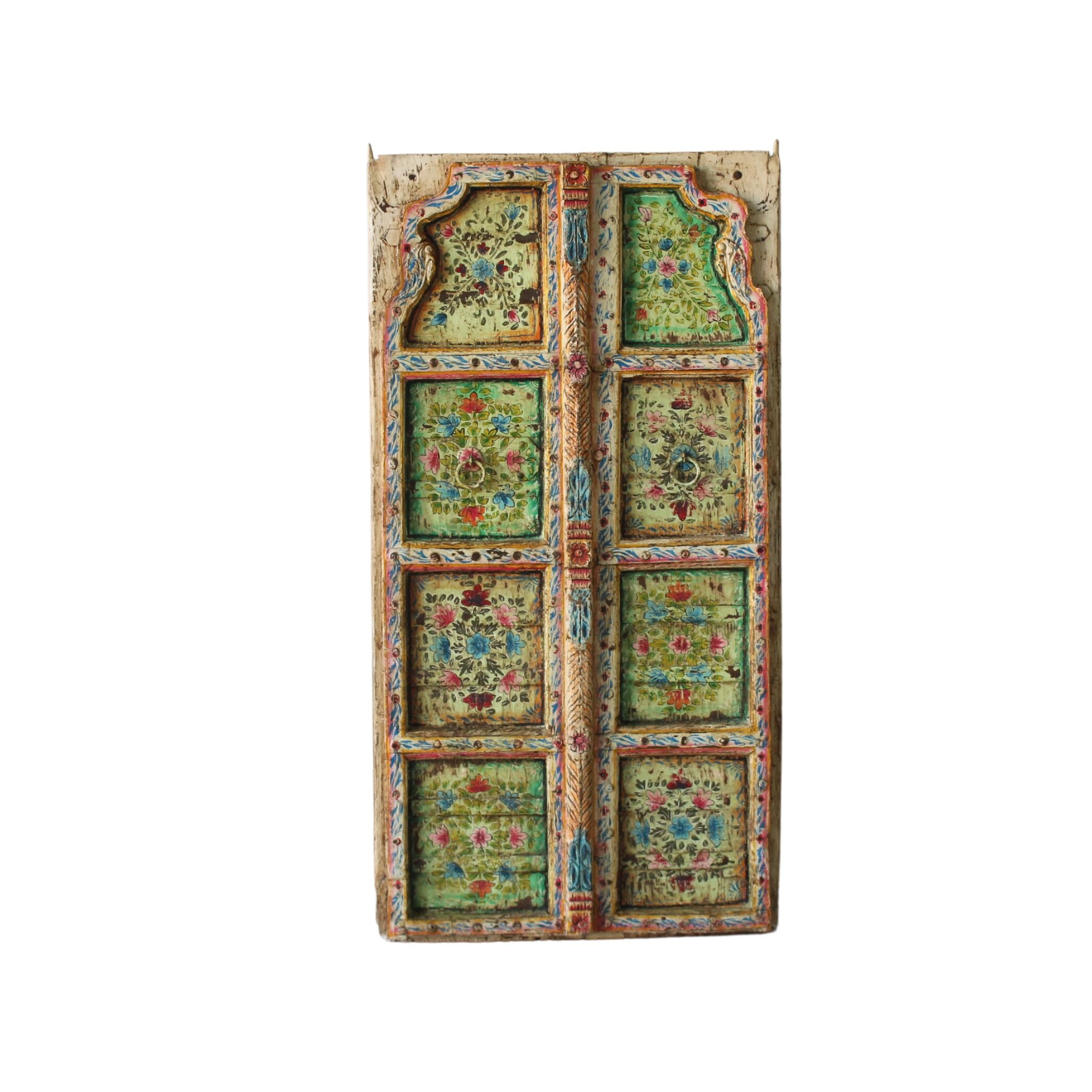 White background image of a Gitra hand-painted teak door panel featuring floral motifs in soft pastels and a carved arched frame—an elegant and unique Indian wall decoration repurposed from antique architecture.
