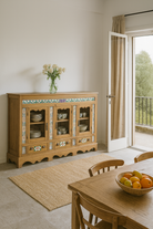 Lifestyle image of an antique Portuguese style South Indian glass display case made from reclaimed teak wood with ceramic inlays – sustainable teak wood furniture with historical and cultural elegance.