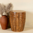 Front view of a round barrel design mango wood side table with hand carved floral designs.