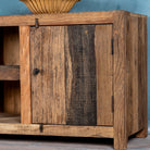Close up image of a rustic sideboard in Driftwood/Wabi Sabi style made from recycled old wood, featuring a natural, weathered finish with two cabinet doors and open central shelving.



