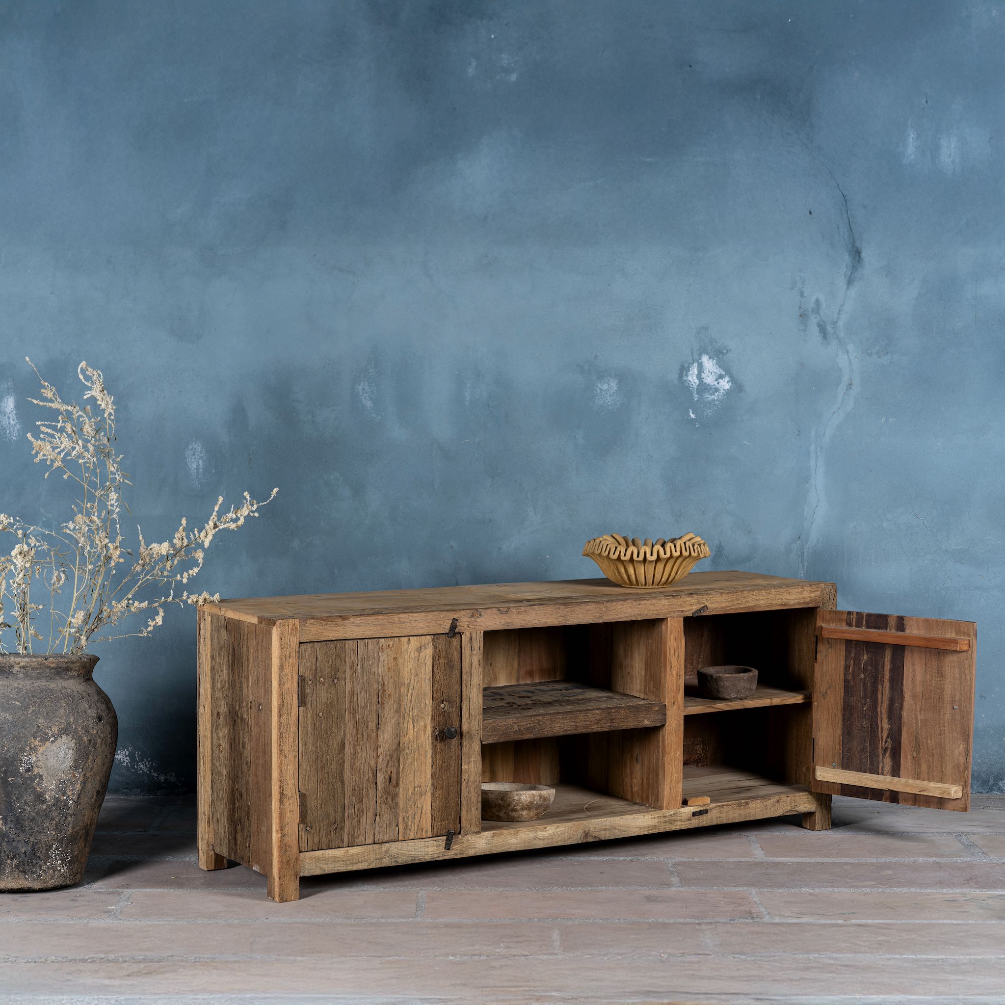 Side view image with open door of a rustic sideboard in Driftwood/Wabi Sabi style made from recycled old wood, featuring a natural, weathered finish with two cabinet doors and open central shelving.


