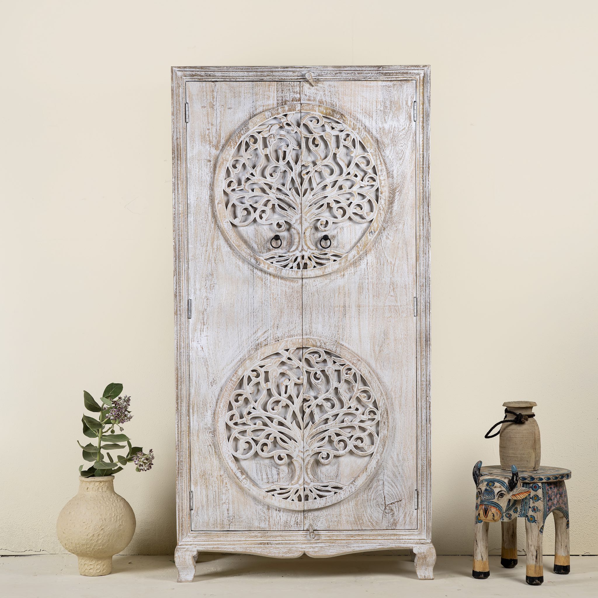Front view of a whitewashed mango wood wardrobe featuring intricate hand-carved double tree of life design on the doors.