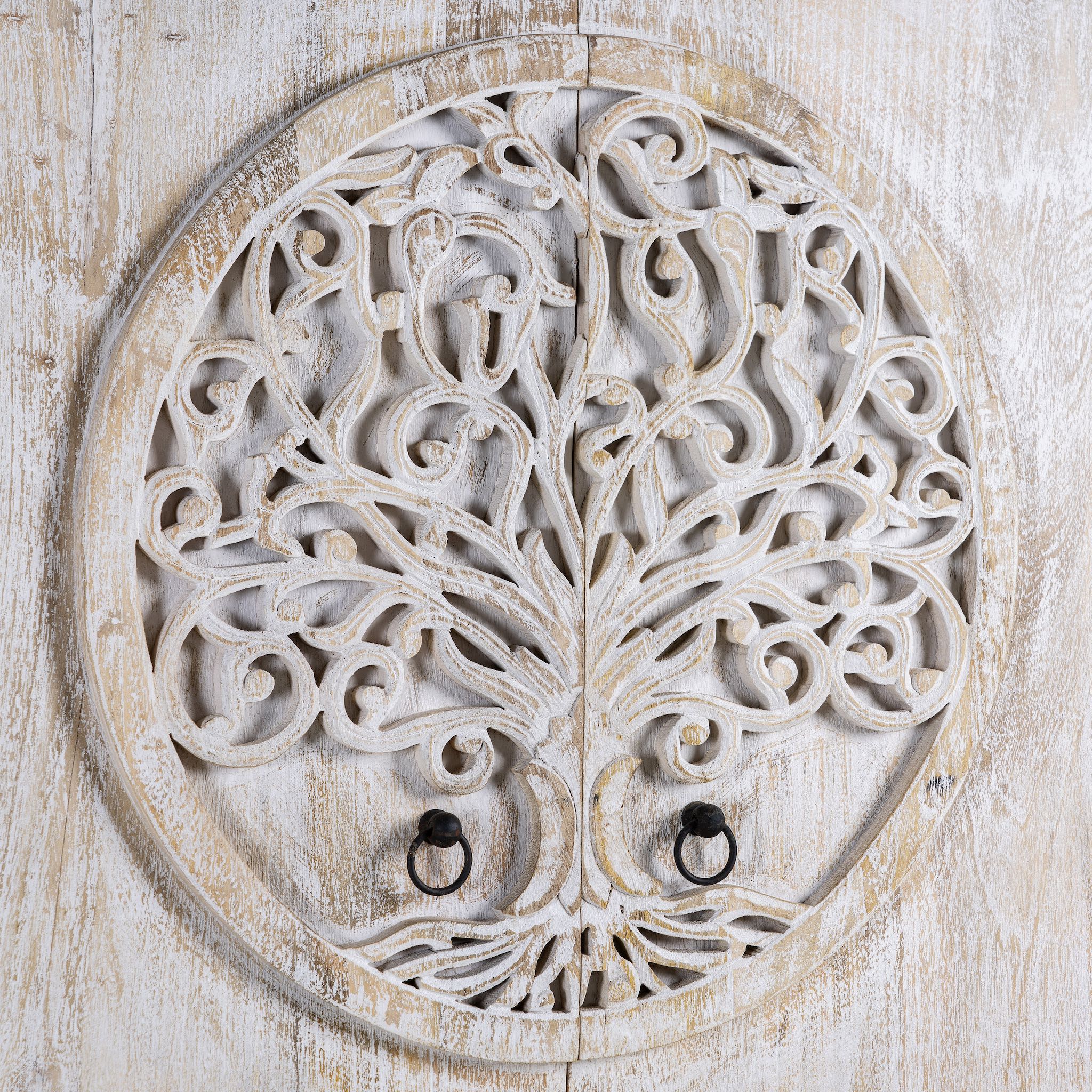 Close up image of a whitewashed mango wood wardrobe featuring intricate hand-carved double tree of life design on the doors.