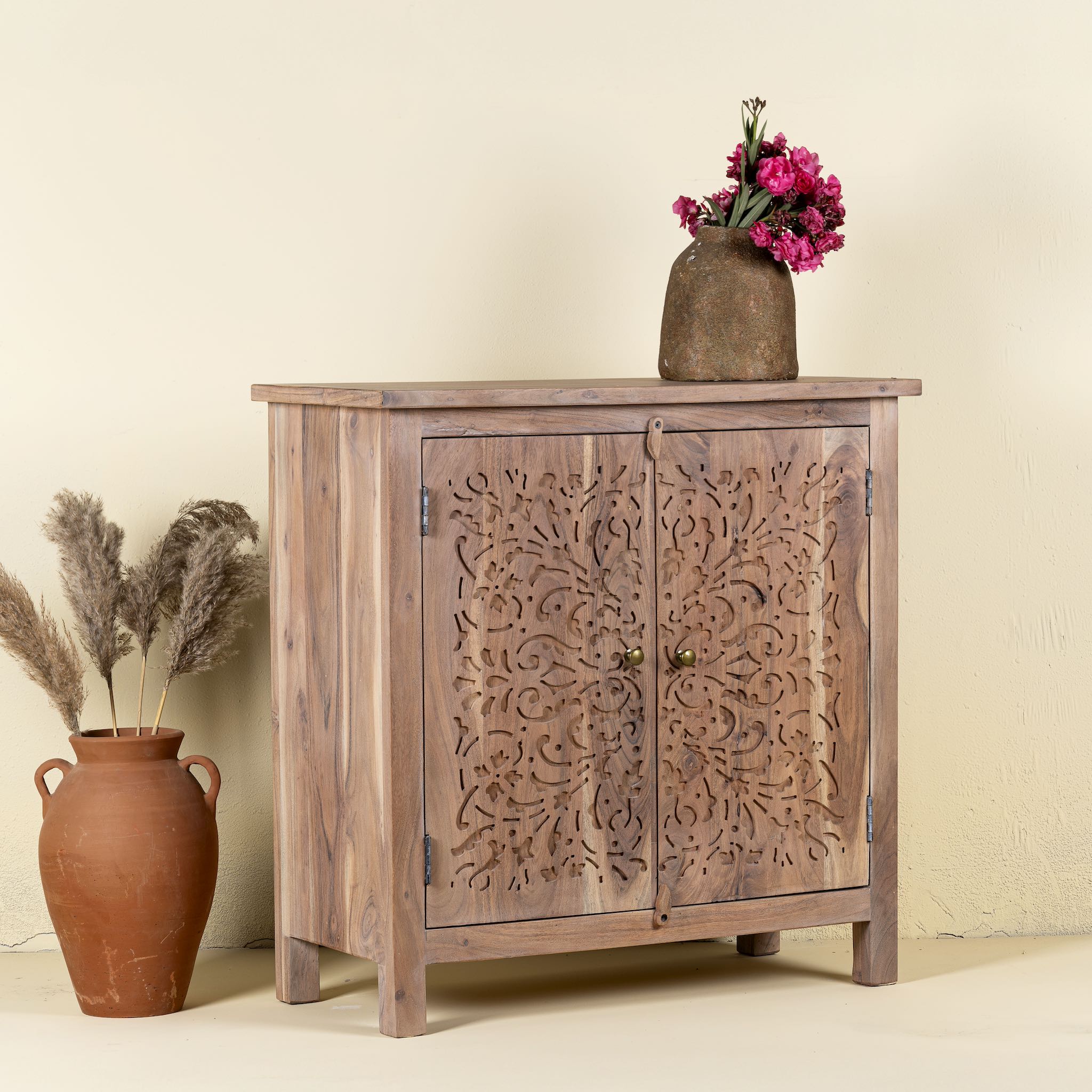 Side view of a Cupboard with floral carvings over both doors made of acacia wood in a living room scene.